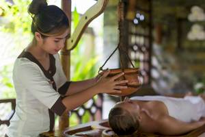 Eine Masseuse gibt einem Gast im Sun Siyam Olhuveli eine Kopfmassage.