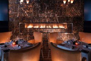Interieur des Fairmont Bab Al Bahr Restaurants mit Marmorwänden und einer großen Feuerstelle.