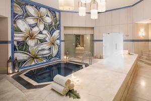 Wellnessbereich im La Pirogue Mauritius Hotel mit Swimmingpool, Kerzen und blauen Wandfliesen.