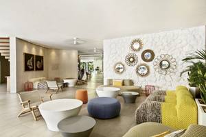 Lobby des La Pirogue Mauritius Hotels mit weißen Wänden, bunten Möbeln und Dekorationen.