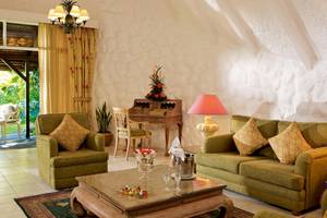 Wohnbereich im La Pirogue Mauritius Hotel mit grünen Sofas, Tisch und Dekor.