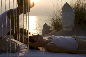 Eine Frau genießt eine Massage am Strand im Sani Club mit Blick auf das Meer.