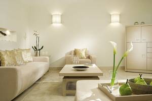 Wohnbereich im Sani Club Hotel mit beigefarbener Couch, Tisch, Kissen und Blumenvase