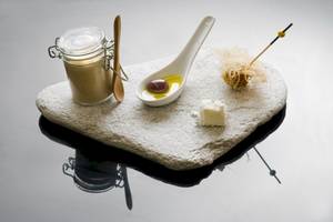 Eine Mahlzeit auf einer Steinplatte mit Sauce, Olive, Käse und einem Löffel.