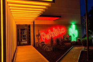 Eingang des Akra Hotels mit leuchtendem Schild und Kakteen in der Nacht