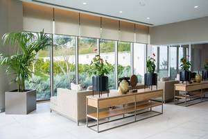 Lobby-Bereich des Akra Hotels mit Sofas, Tischen, Blumen und großen Fenstern.