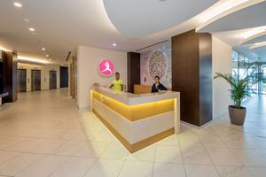 Empfangsbereich des Akra Hotels mit zwei Mitarbeitern und einer grünen Pflanze