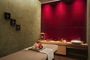 Spa-Behandlungsraum im Akra Hotel mit roten Wänden, zwei Massagetischen und einem Waschbecken.
