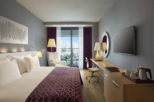 Innenansicht eines Zimmers im Akra Hotel mit Bett, Schreibtisch und Fernseher.