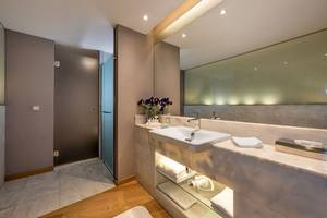 Badezimmer im Akra Hotel mit großem Spiegel und Blumen auf dem Waschtisch.