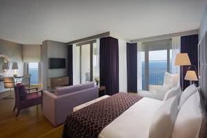 Suite im Akra Hotel mit Meerblick, inklusive Bett, Sofa, Fernseher und Balkon.