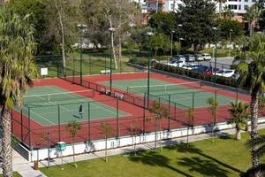 Tennisplatz im Freien Bereich des Akra Hotels mit einem Spieler, der Tennis spielt.