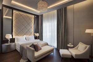Schlafzimmer im Akra Hotel mit einem Bett, einer Couch, Stühlen und Lampen.