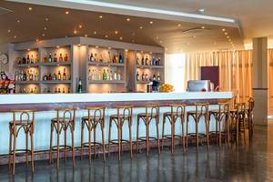 Barbereich im Themis Beach Hotel mit vielen Flaschen und Stühlen.