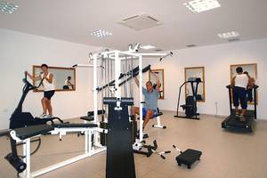 Fitnessraum im Themis Beach Hotel mit Personen auf Laufband und Kraftgeräten.