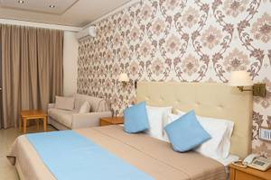 Hotelzimmer mit Meerblick und Balkon im Themis Beach Hotel, inklusive Schreibtisch, Stuhl, Sofa und Fernseher.