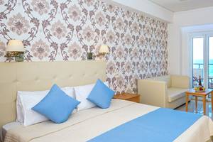 Das Zimmer im Themis Beach Hotel mit einem Bett, Kissen, Couch, Tisch und Blick auf das Meer.