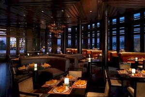 Innenansicht des Al Baleed Resort Salalah by Anantara Restaurants mit runden Tischen und Kerzen.