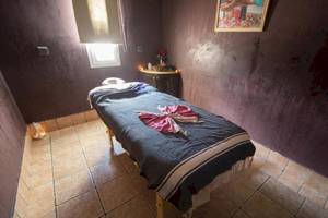 Massageraum im Green Palm Hotel mit einem Behandlungstisch und einem Kerzenlicht.