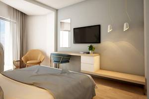 Innenansicht eines Hotelzimmers im NissiBlu Beach Resort mit Bett, Schreibtisch, Fernseher und Lampe.