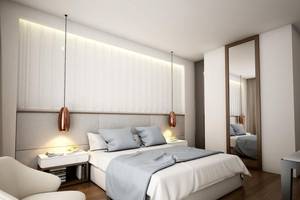 Innenansicht eines Schlafzimmers im NissiBlu Beach Resort mit weißem Bett, grauen Kissen und modernen Lampen.