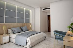 Schlafzimmer im NissiBlu Beach Resort mit Bett, Nachttischen, Lampen und einem Stuhl.