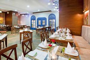 Innenansicht des Restaurants des Adalya Ocean Deluxe Hotels mit gedeckten Tischen und dekorierten Wänden.