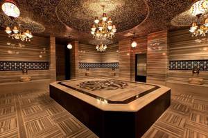 Innenbereich der Sauna im Adalya Ocean Deluxe Hotel mit Marmorboden und dekorativen Kronleuchtern.