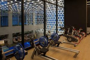 Fitness-Center im Maxx Royal Kemer Resort mit gemusterter Decke und Reihe von Crosstrainern.