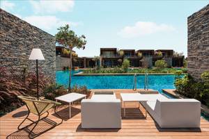 Pool-Loungebereich im Maxx Royal Kemer Resort mit weißen Möbeln und einer steinernen Umgebung.