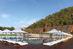 Poolbereich des Maxx Royal Kemer Resort mit vielen weißen Sonnenliegen und Sonnenschirmen.