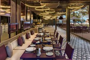 Innenansicht des Restaurants im Maxx Royal Kemer Resort mit gedeckten Tischen und Blick aufs Meer.