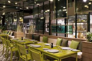 Innenbereich des Restaurants im Maxx Royal Kemer Resort mit grünen Tischen und Stühlen.