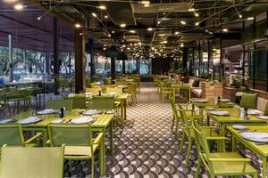 Innenbereich des Restaurants im Maxx Royal Kemer Resort mit grünen Tischen und Stühlen.