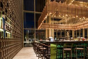 Innenansicht der Bar im Maxx Royal Kemer Resort mit geschwungener Theke und modernen Stühlen.