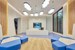 Lobby des Maxx Royal Kemer Resort mit blauen Sitzmöbeln, weißem Schreibtisch und Fernseher.