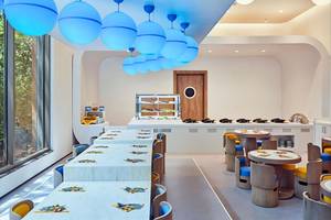 Innenbereich des Maxx Royal Kemer Resorts mit langen Tischen, runden Stühlen und blauen Pendelleuchten.