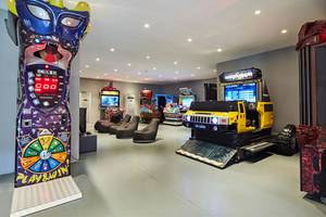 Spielzimmer im Maxx Royal Kemer Resort mit verschiedenen Arcade-Spielen und Sitzgelegenheiten.