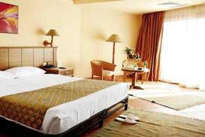 Ein elegantes Hotelzimmer im Charmillion Garden Aqua Park mit Doppelbett, Nachttischen, Stühlen und Gemälde an der Wand.