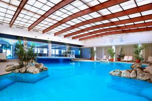 Innenpool im Aquila Rithymna Beach Hotel mit blauem Wasser und steinernen Dekorationen.