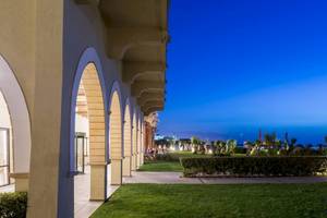 Außenansicht des Aquila Rithymna Beach Hotels bei Abend mit beleuchteter Gartenlandschaft.