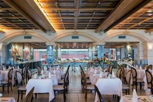Innenansicht des Restaurants im Aquila Rithymna Beach Hotel mit gedeckten Tischen und Stühlen.