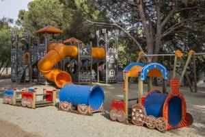 Spielplatz im Falkensteiner Resort Capo Boi mit einer Burg, Rutsche und Zugspielzeug.