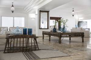 Wohnzimmer im Falkensteiner Resort Capo Boi mit zwei Sofas, Holztischen und blauen Vasen.