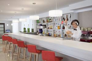 Eine Mitarbeiterin des HSM Venus Playa Hotel serviert ein Getränk an der Bar.