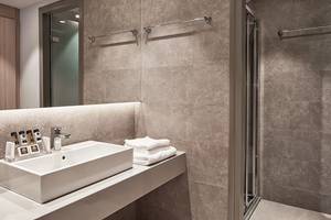 Badezimmer im Porto Bello Royal Hotel mit Waschbecken, Handtüchern und Duschbereich.