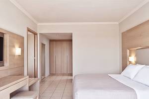 Schlafzimmer im Porto Bello Royal Hotel mit Doppelbett und modernen Holzmöbeln.