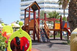 Kinderspielplatz im Freien vor dem Crystal Springs Beach Hotel mit bunten Spielgeräten und Gebäude im Hintergrund.