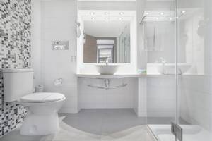 Modernes Badezimmer im Vassos Nissi Plage Hotel mit weißem Design und Glasdusche.