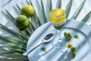 Getränke im Glas auf einem weißen Teller mit Limetten und Blumen